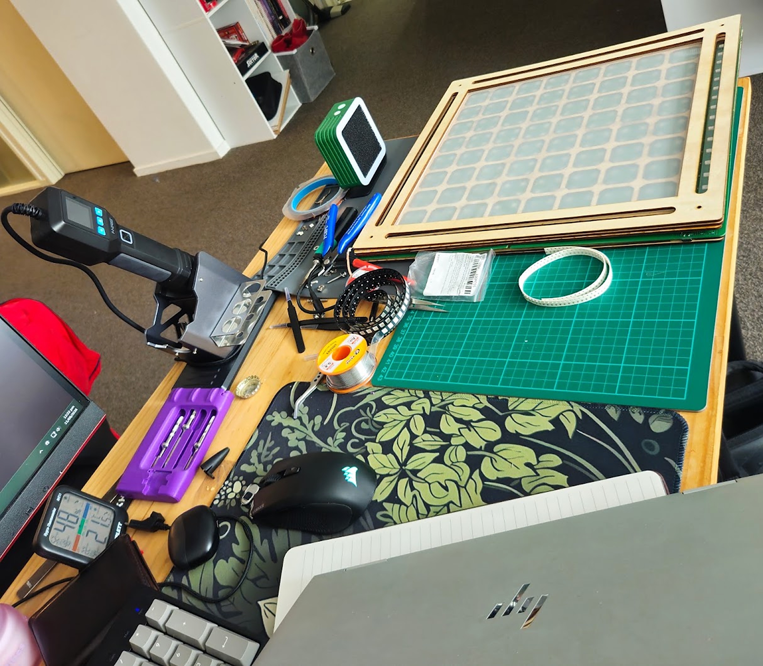 Soldering at home, with the wooden chess grid frame beside the board