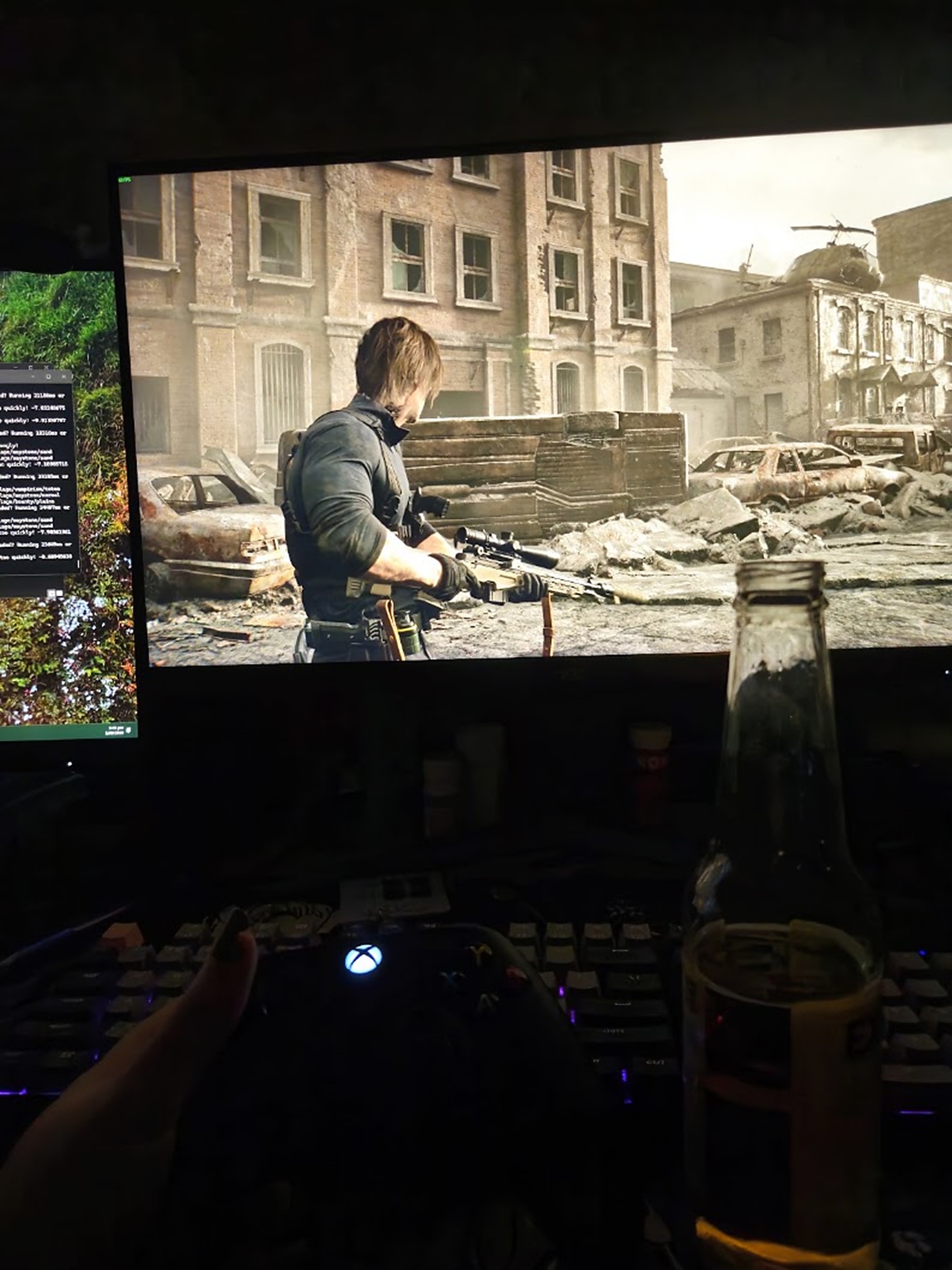 Resident Evil Requiem on the monitor at Ara's desk, with an Xbox controller